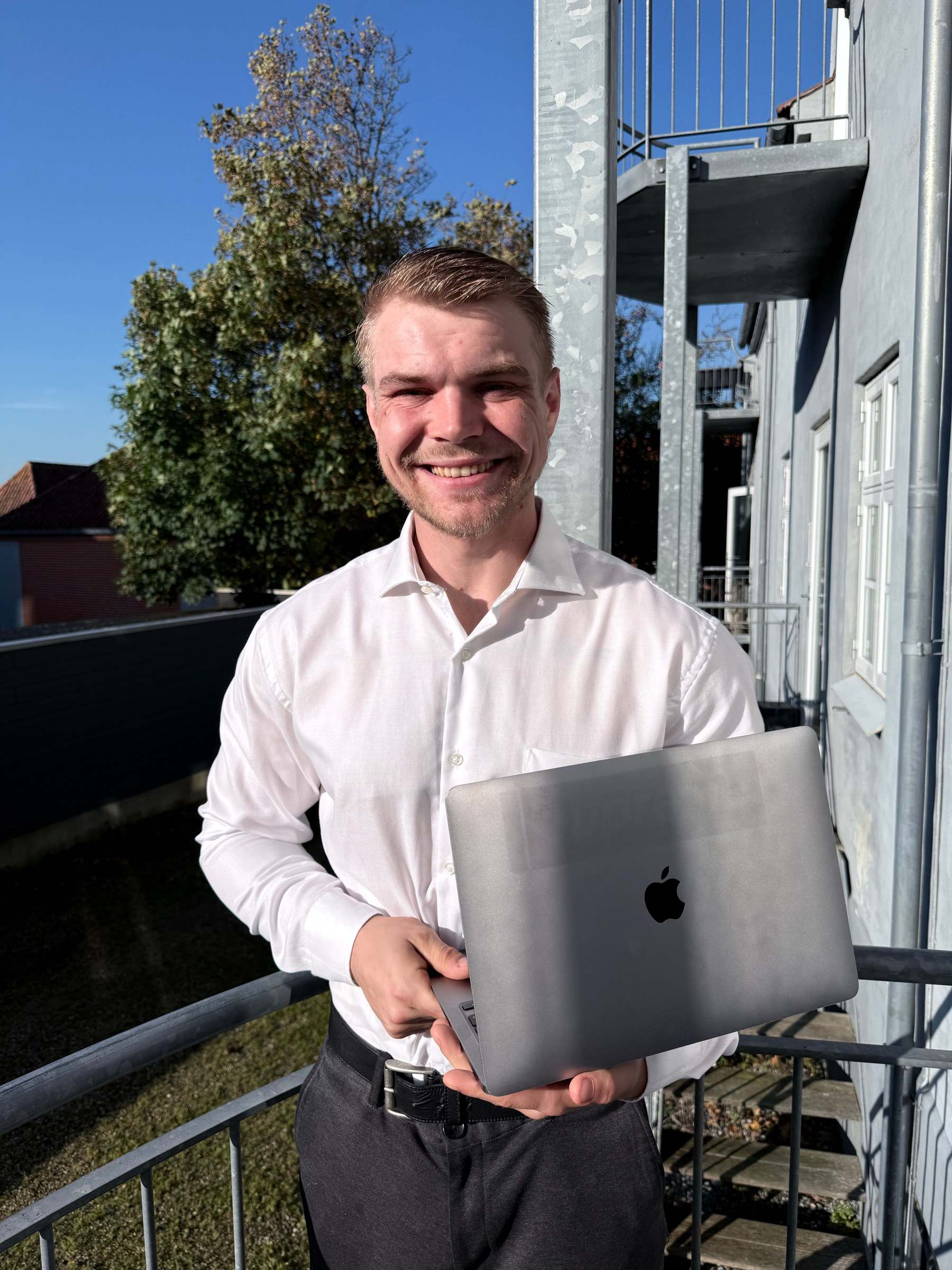 Mathias Sørsdal står udenfor i solen med en bærbar i hænderne